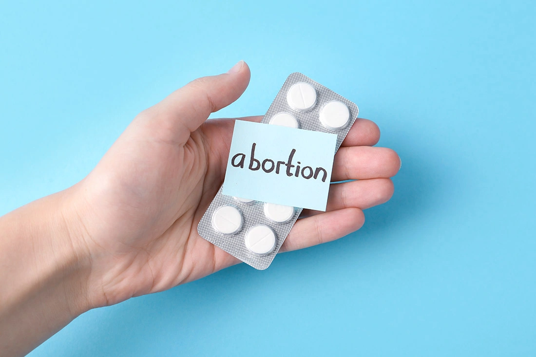 A woman holding a pack of abortion pills